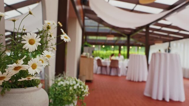 White daisy arrangement in elegant banquet hall with cocktail tables and soft daylight