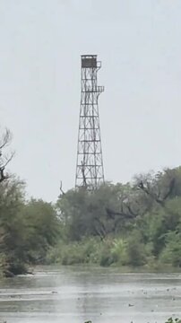 Landscape view of a rural canal and a metal watchtower