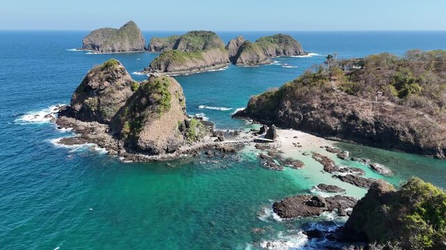 Stunning aerial footage of steep rocky cliffs and tropical islets surrounded by crystal-clear turquoise ocean waters