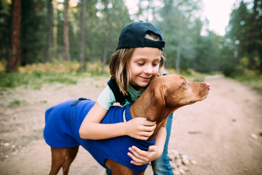 Girl hugging dog in forest