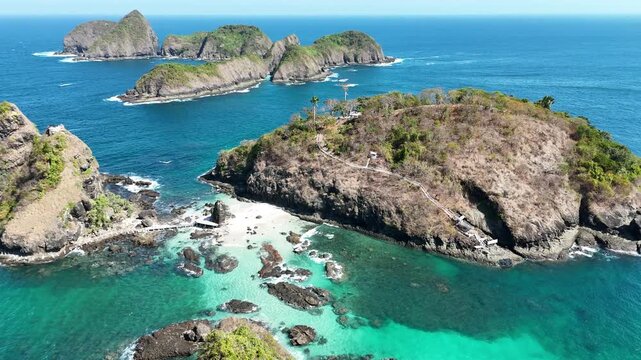 Stunning aerial footage of steep rocky cliffs and tropical islets surrounded by crystal-clear turquoise ocean waters