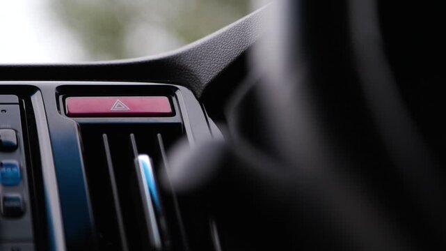 Driver finger pressing car hazard warning light button. Automated vehicle control panel interaction. Safety signaling system activated in modern automobile interior.