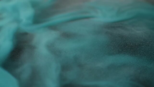 Swirling teal smoke threads drifting over a soft gray backdrop, creating abstract, flowing patterns