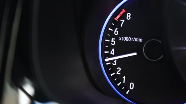 Car tachometer needle rising on the dashboard. Engine revolutions per minute display showing accelerating speed. Modern vehicle gauge monitoring automotive performance.