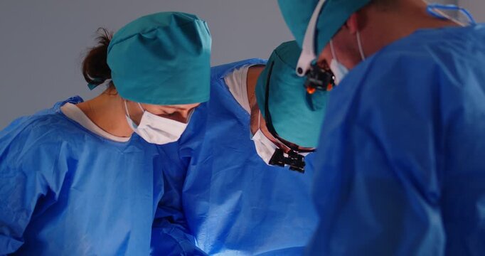 Surgeon doctors operating on patient, concentrated professional surgical nurse, anesthesiologist in physical therapy apparel, gown, surgical cap, sanitary clothing medical practice operation