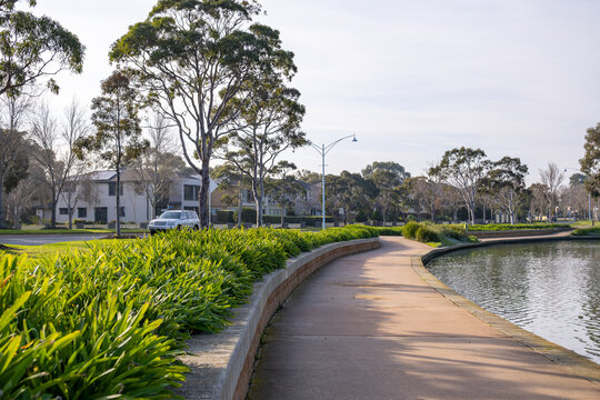 A well-landscaped path curves along a raised lakeside garden bed beside waterfront homes in Sanctuary lakes, Point Cook, Melbourne Australia. Desirable public infrastructure and liveable environment