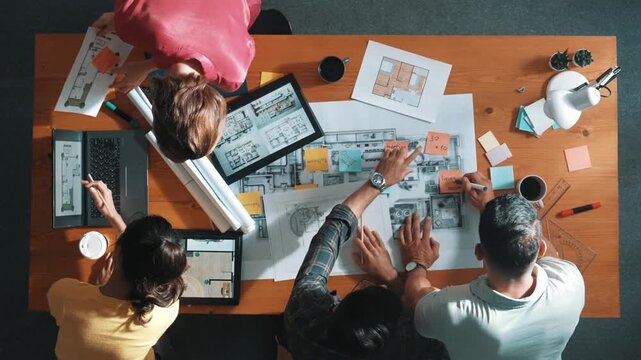 Civil engineer team checking at sticky note while standing at meeting. Top view of designer working and looking at note stick at blueprint while colleague explaining and working together. Symposium.