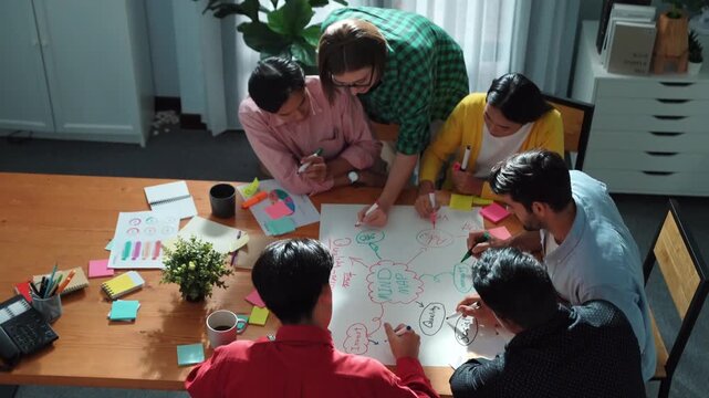 Top down view of smart business team in casual cloth brainstorming marketing idea and writing mind map together. Professional creative people using mind map to share and exchange idea. Convocation.