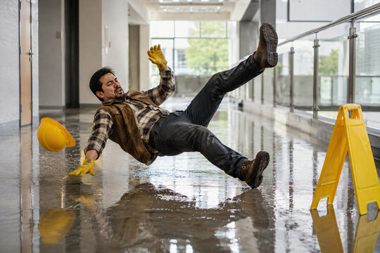 A man slipping and falling backwards on a wet and slippery floor
