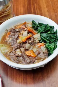 Indonesian tumis daging sapi with vegetables in light oyster sauce gravy. Stir fried beef with carrots garlic and leafy greens in savory Asian style dish.