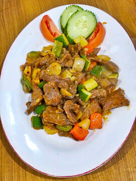 Close up of homemade beef stir fry with vegetables including carrot zucchini and garlic served on white plate. Healthy protein rich Asian style dish with natural presentation.