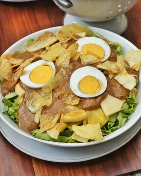 Fusion huzarensalade with boiled eggs potato chips lettuce and peanut sauce dressing. Unique Asian European salad with rich texture and authentic presentation.