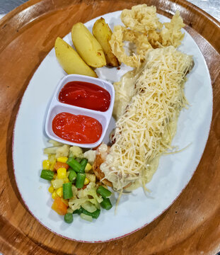 Western-style chicken steak topped with melted mozzarella and grated cheese, served with potato wedges, mixed vegetables and dipping sauces on a rustic wooden tray.