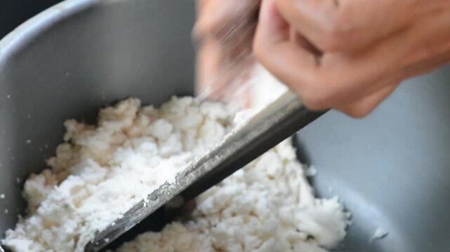Hands grind coconut in a green bowl