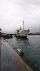 Fototapeta premium Traditional Istanbul ferry arriving at Karakoy pier on a cloudy day