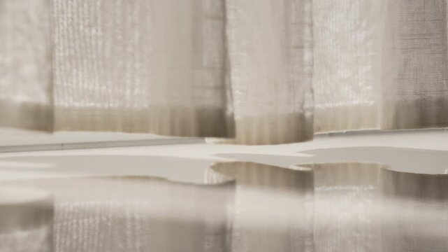 Close up of white curtain hem waving gently with smooth reflection on glossy polished floor under soft morning light. Elegant text space background