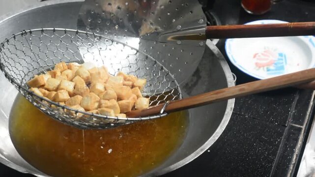 Close-up of frying colorful Indonesian crackers in hot oil. Traditional snack preparation featuring vibrant crackers, authentic local cuisine, homemade cooking, crispy texture, and delicious street fo