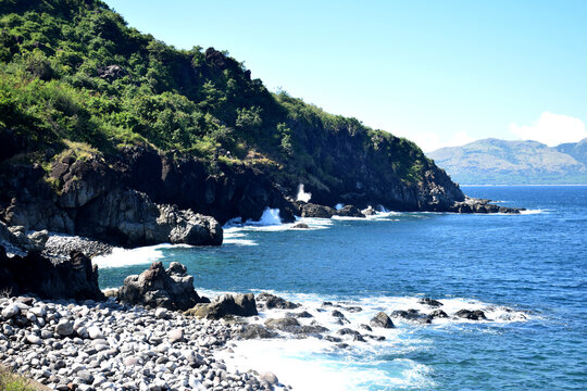 The crashing waves of a pristine beach around Nuca Molas Island, West Manggarai, Indonesia, set against clear weather and a beautiful blue sky.