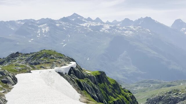 Slow motion pan over a lingering summer snowfield on a glacially