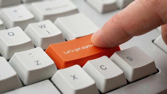 Computer keyboard with orange button, hand pressing key, Let's get started text