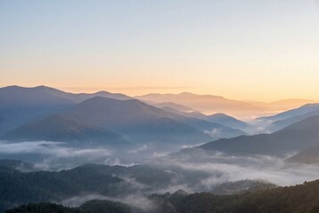 Fototapeta premium Misty mountain range at sunrise with layered blue peaks 