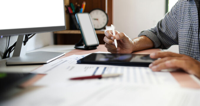 close-up shot, businessman using digital tablet working on table with document and desktop computer