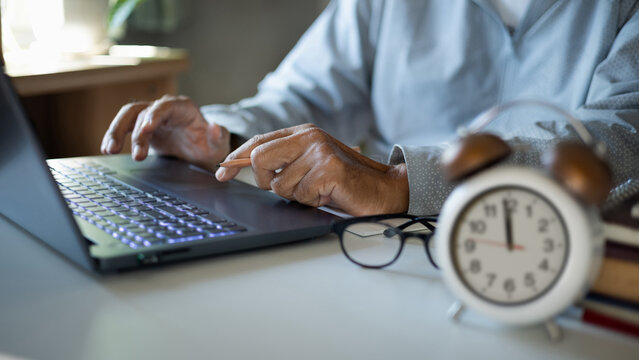 close up shot, asian man in casual clothes using laptop working on desk before taking a break at lunch time