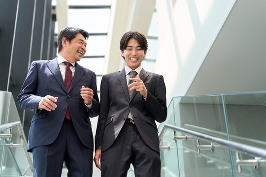 オフィスの階段を歩くアジア人ビジネスパーソン
