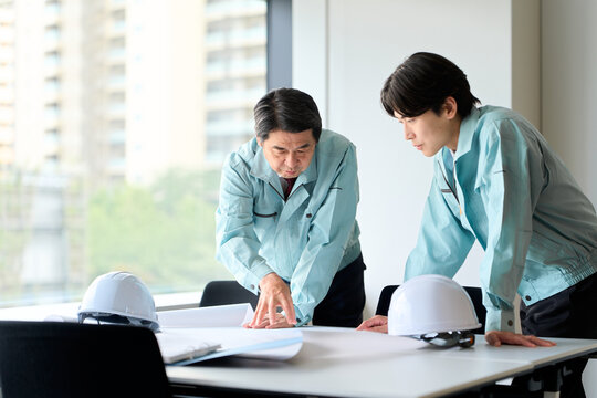 打ち合わせをする作業服を着た男性