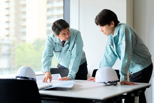 打ち合わせをする作業服を着た男性