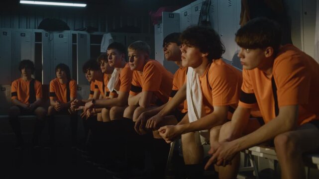After Training Session, Teenage Soccer Team Sits in Low Key, Locker Room, Seriously Contemplating Performance. Boys Expressions Thoughtful and Concerned as Receive Constructive Feedback From Coach.