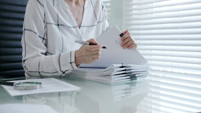 Financial auditor reviewing company documents, checking tax compliance reporting, conducting a detailed investigation, and thoroughly analyzing business paperwork for legal adherence