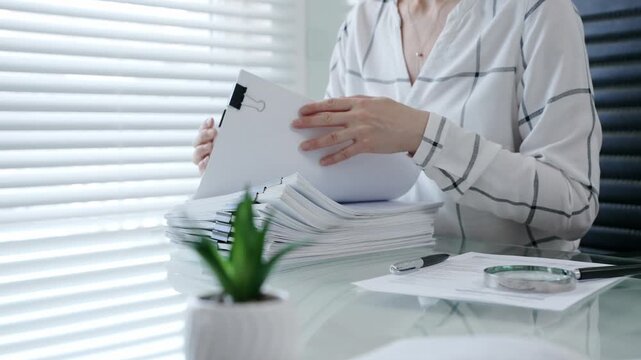 Financial auditor reviewing company documents, checking tax compliance reporting, conducting a detailed investigation, and thoroughly analyzing business paperwork for legal adherence