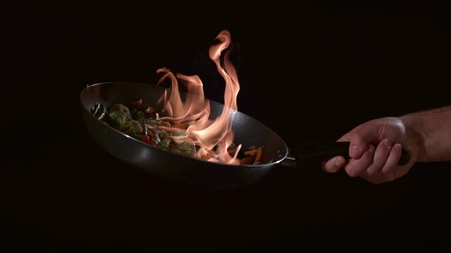 Chef flamb s vegetables in wok pan during cooking process in kitchen