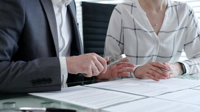 Business professionals reviewing legal contracts and important documents with a magnifying glass, performing careful examination and due diligence for risk assessment