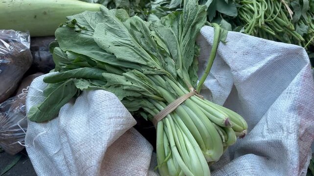 Fresh green choy sum bundle on sack at traditional Asian market
