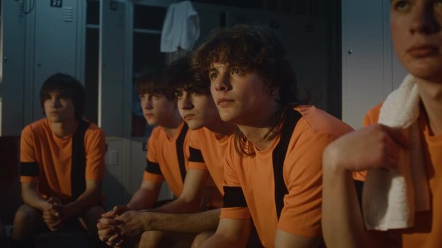 Serious and Determined Expressions of Teenage Football Squad During Post Workout Briefing. Sitting on Locker Benches, Absorb Tactical Advice and Motivational Words. Team Unity, Mental Toughness.
