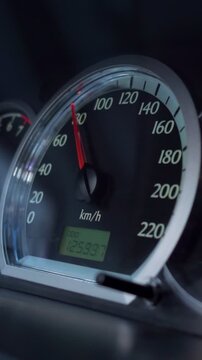 Close up of a car's speedometer with the red needle indicating the vehicle's speed in kilometers per hour while driving, showing the modern instrument panel and the digital odometer display