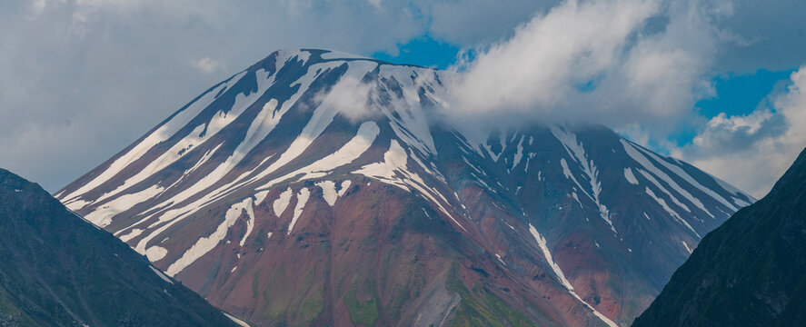 Red volcanic mountain peak with melting snow stripes in Georgia with copy space