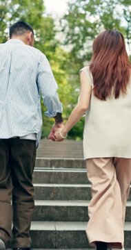 Couple, running and holding hands on stairs in park for outdoor travel, fun bonding or tourism. Back view, man and woman on staircase for weekend, holiday or romantic adventure in nature together