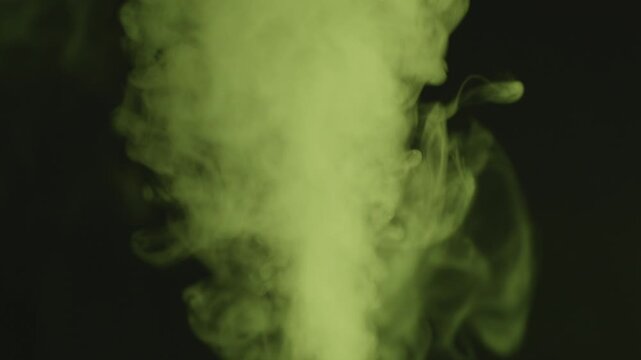 Yellow-Green Smoke Pulsing Twice from Weak to Strong on Black Background