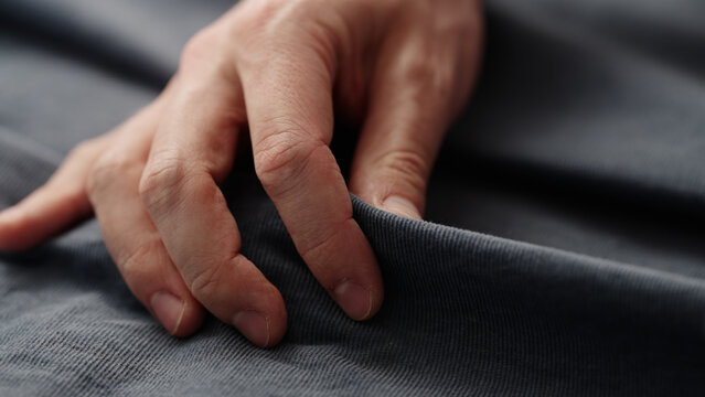 man manually check corduroy blue color cotton fabric for clothing with hands