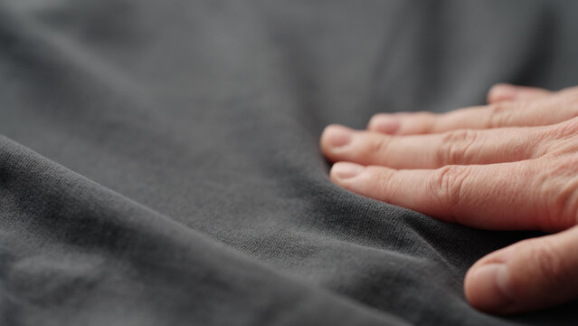 man manually check gray color cotton fabric for clothing with hands