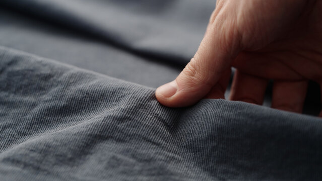 man manually check corduroy blue color cotton fabric for clothing with hands