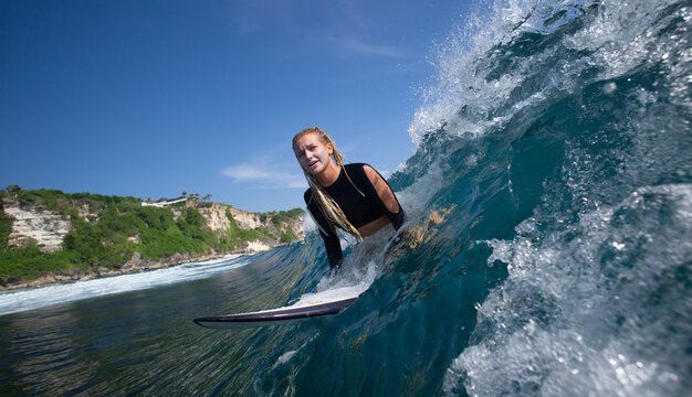Blonde Surfer Navigating Powerful Ocean Wave Near Tropical Coast