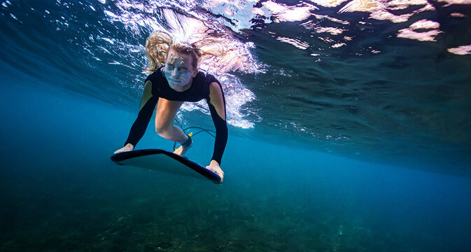 Underwater Portrait of Female Surfer Holding Board in Deep Blue