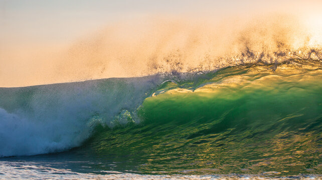 Massive Turquoise Ocean Wave Breaking with Golden Sunlit Spray
