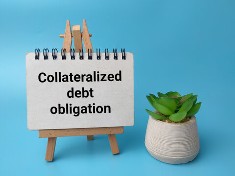 A small wooden easel supporting a notebook that reads Collateralized debt obligation next to a potted green succulent