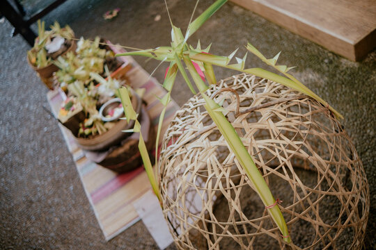  Traditional Balinese Hindu offerings (banten and canang sari) beautifully arranged on ceremonial trays with woven palm leaf decorations and burning incense inside a Balinese te