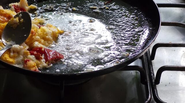 Oil bubbling in a pan with an egg and red chili.